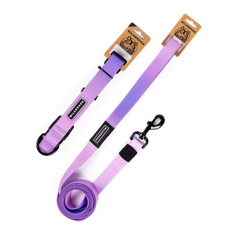 The Aurora Waterproof Leash + Collar Bundle in lavender purple features black metal hardware and Wilderdog-branded brown tags on the handles. Shown coiled and uncoiled, this durable, stink-proof dog gear is perfect for any outing.