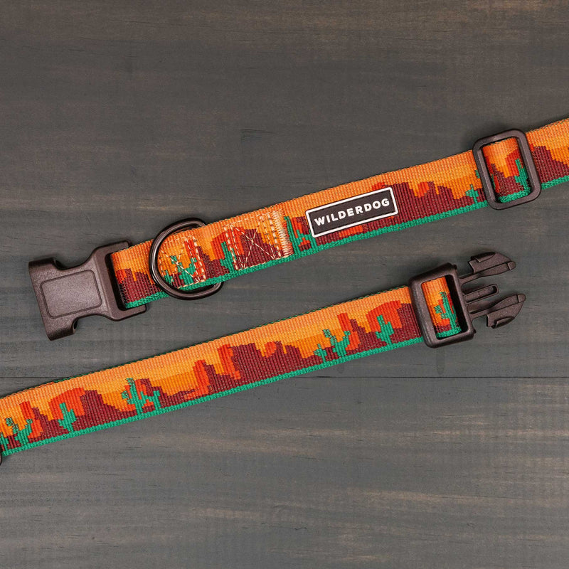 Two Moab Ultralight Collars with ultralight nylon webbing and a desert-inspired design in orange, brown, and green. Each features plastic buckles, a metal D-ring, "Wilderdog" label, and comes with a lifetime warranty.