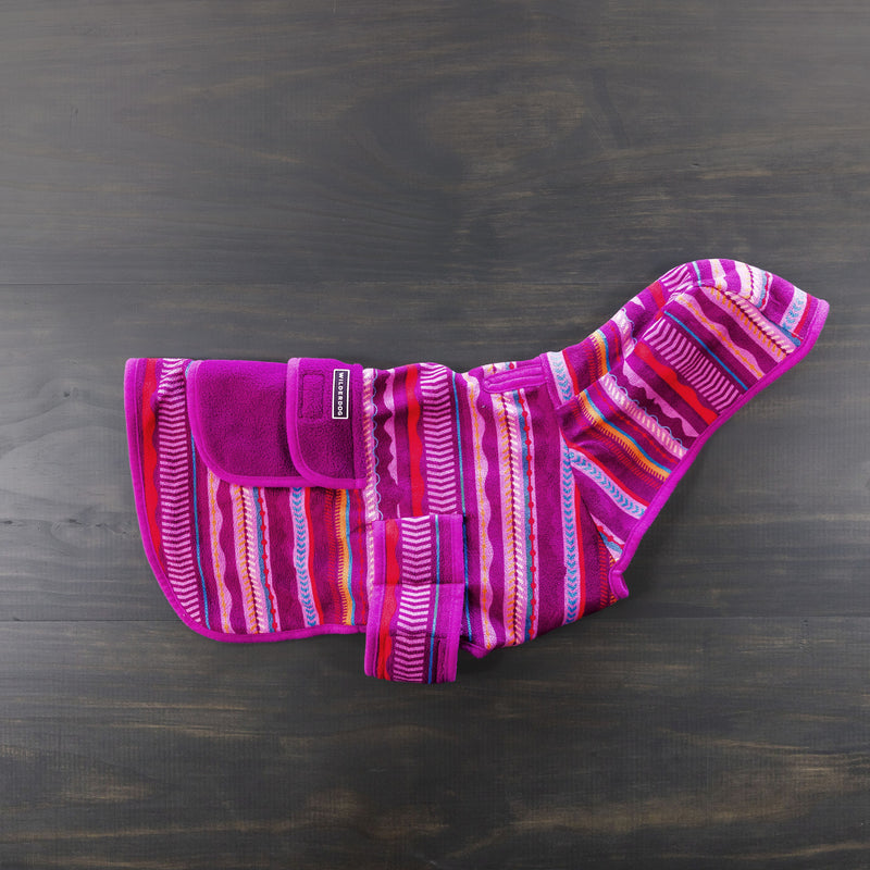 This eye-catching Dawn Fleece Jacket features vibrant horizontal stripes in shades of purple, pink, orange, and white. It comes with a convenient Velcro closure and looks stunning laid flat on a dark wooden surface. Pair it with a Wilderdog leash for the ultimate walk-ready ensemble.