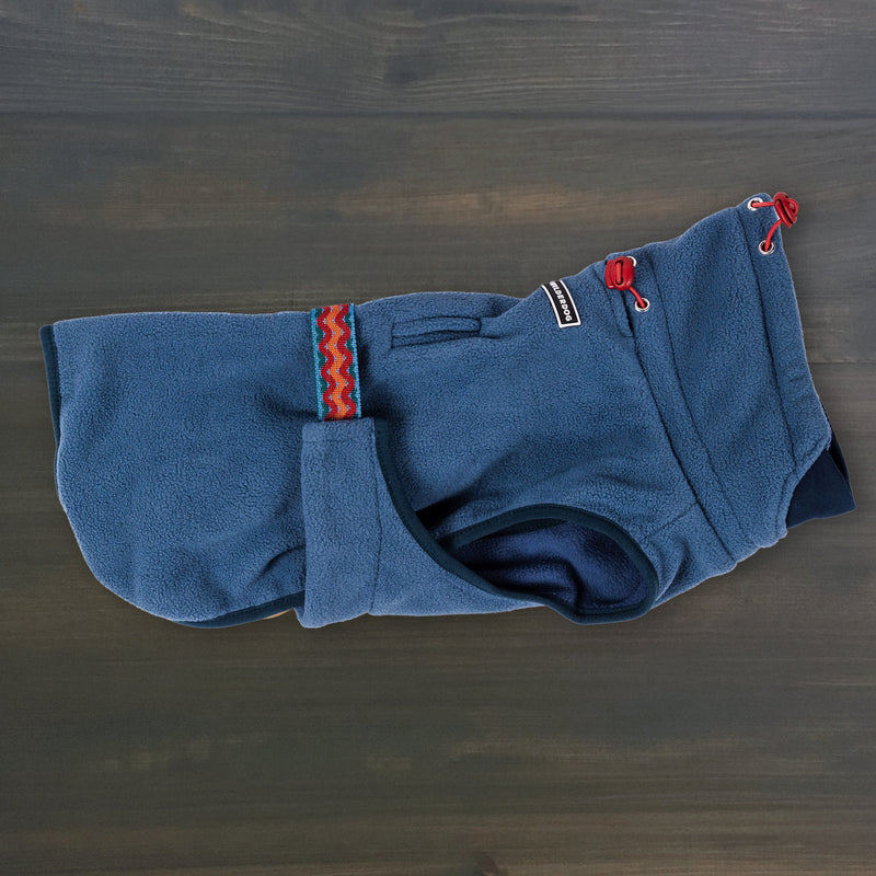 Pro Fleece Jacket: blue dog fleece with patterned strap & red drawstrings, shown on dark wood.