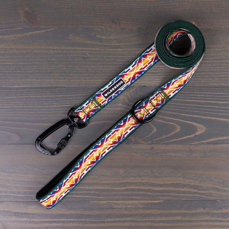 The Rainbow Ultralight Leash from Wilderdog’s Ultralight Collection, featuring a vibrant geometric pattern in red, yellow, green, and blue on a rustic wooden surface. This colorful dog leash includes a black metal clasp and padded handle for both style and comfort.