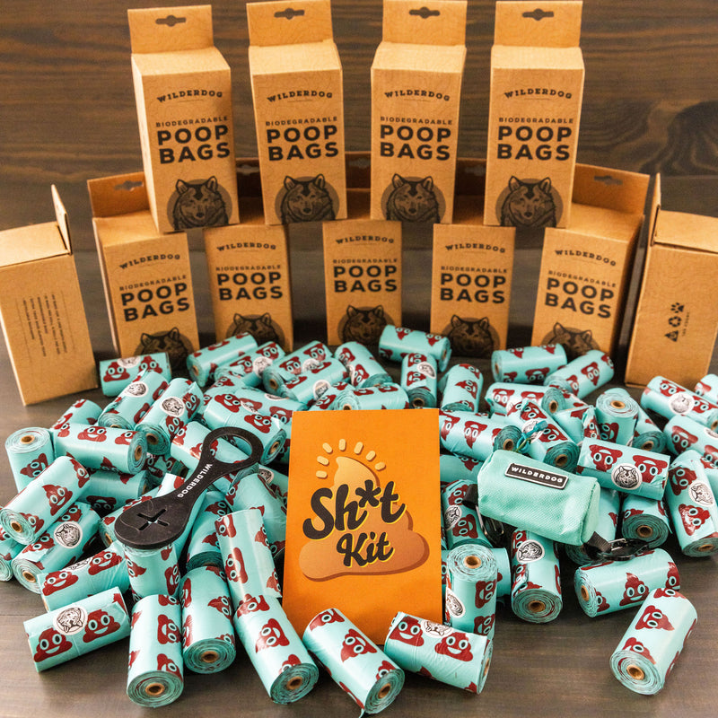 Several Sh*t Kit boxes are displayed in the background, with light blue poop bag rolls, a black Crap Carrier dispenser, a Seafoam Poop Bag Holder pouch, and an orange Sh*t Kit card featured at the center.