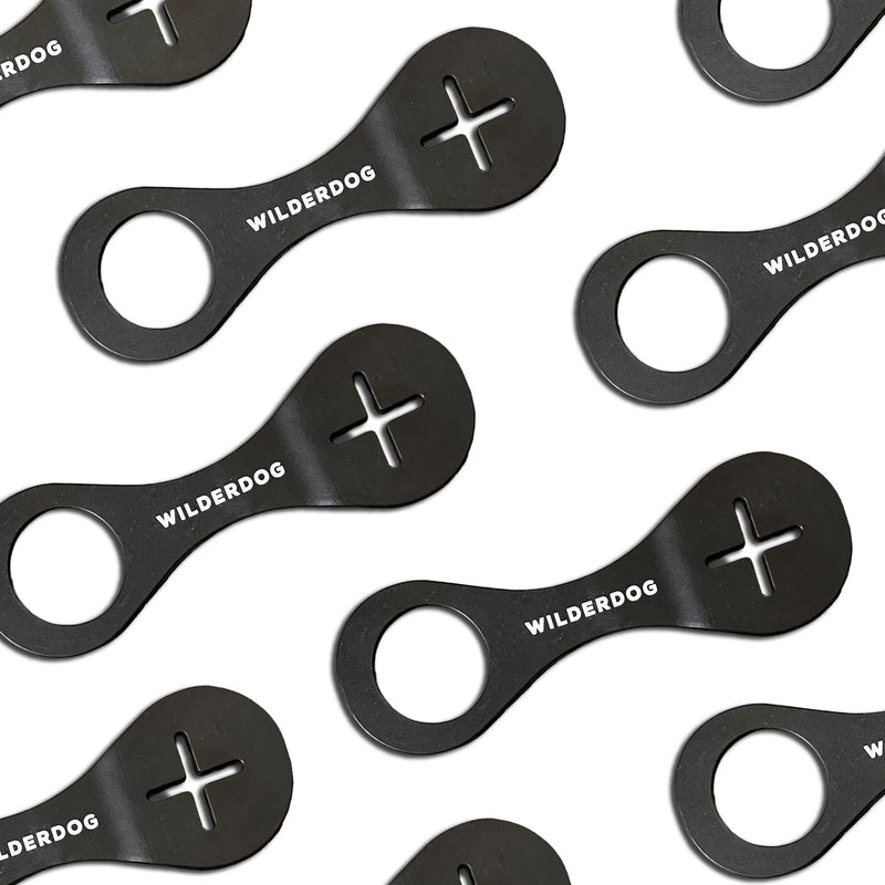 Several black Crap Carrier™ bottle openers, a handy leash add-on or hands-free poop bag holder, arranged on white.