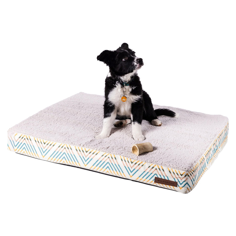 Black and white puppy on a Memory Foam Dog Bed with washable cover, chewing a toy and looking to the side.