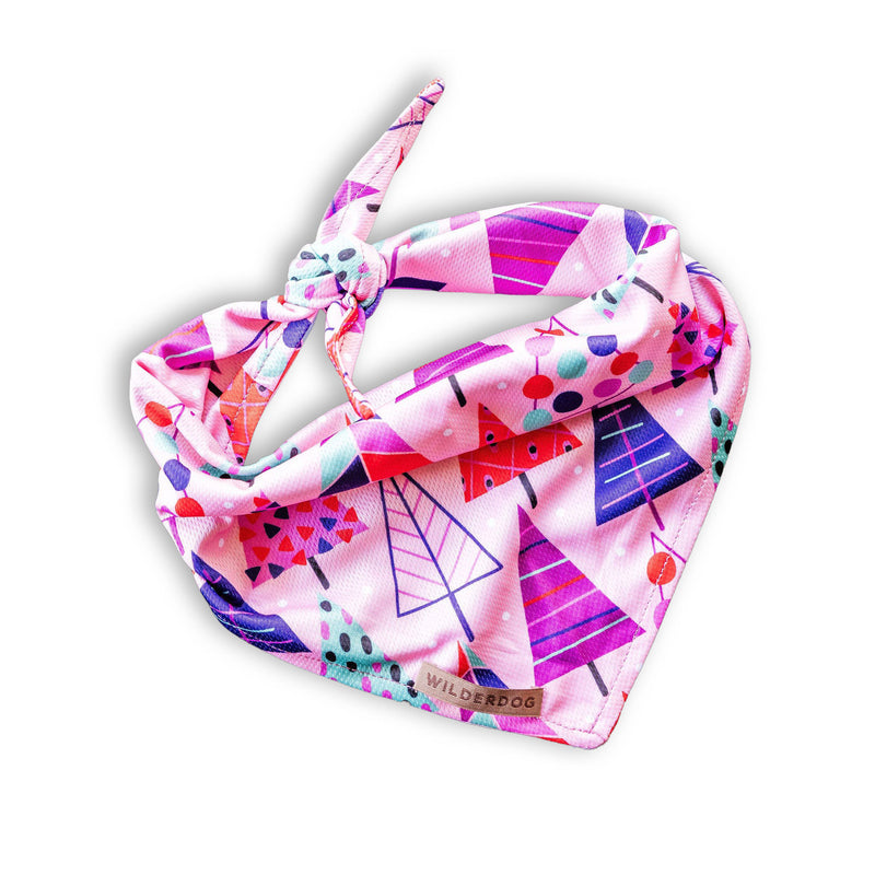 The Sugarplum Bandana is a pink, knot-tied dog bandana with geometric trees and a stylish Wilderdog tag.