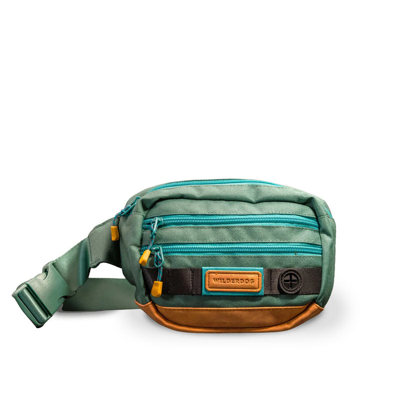 Green & brown Utility Pack, vegan dog treat bag with blue zippers & yellow pulls, shown on white background.