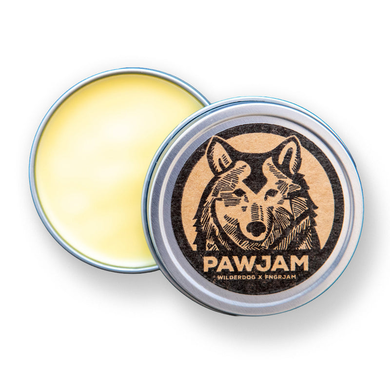 A partially open PAWJAM tin with a wolf logo shows yellow balm for soothing dry, cracked dog paws.