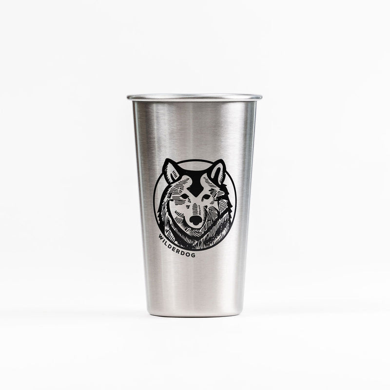The Wilderdog x MiiR Pint Glass (16oz) showcases a black line wolf face drawing with “WILDERDOG” below, set on a plain white background for a versatile look.